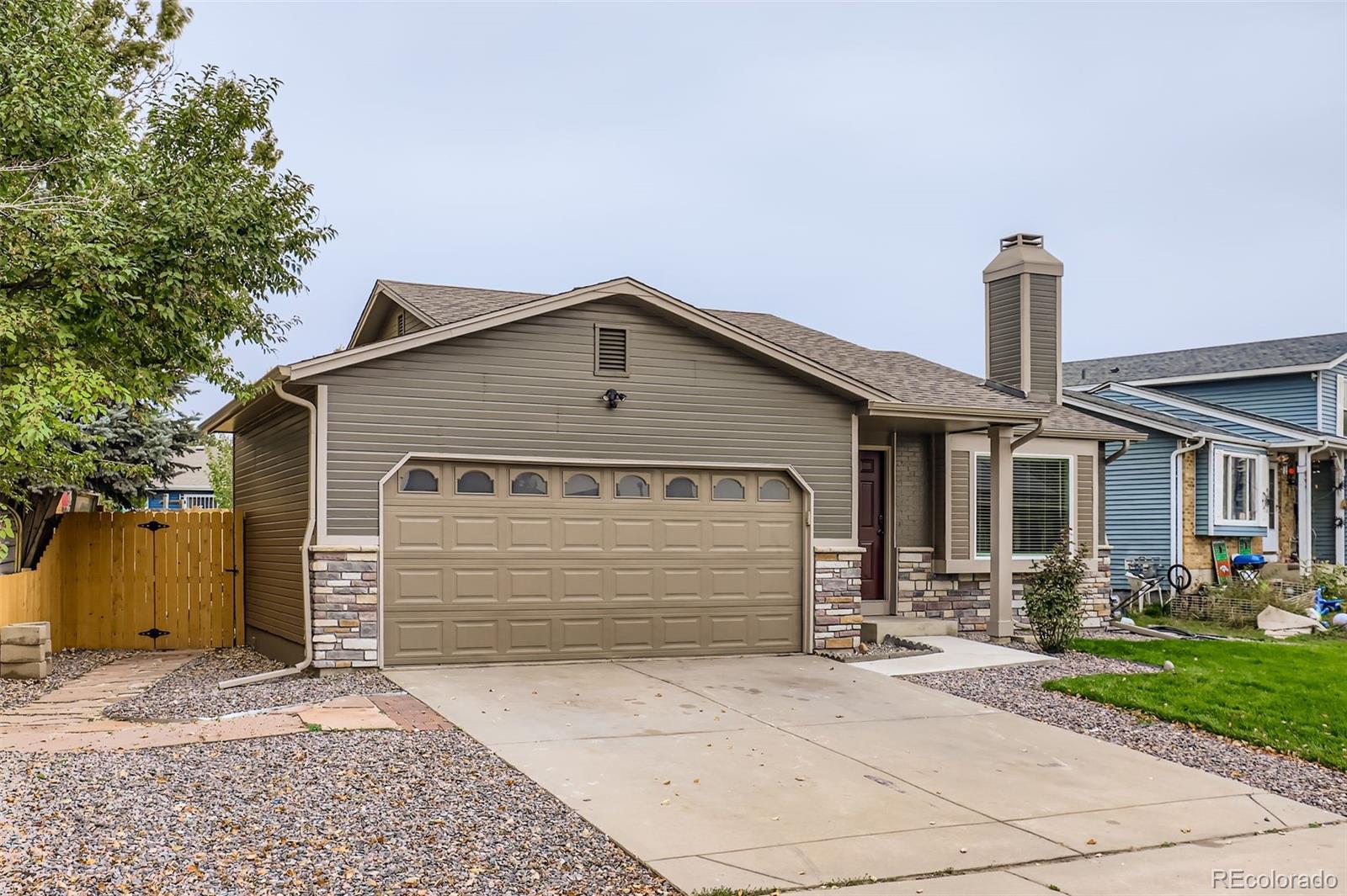 4465 Durham Court Denver, CO 80239 - Photo 2 of 28 a front view of a house with a yard and garage