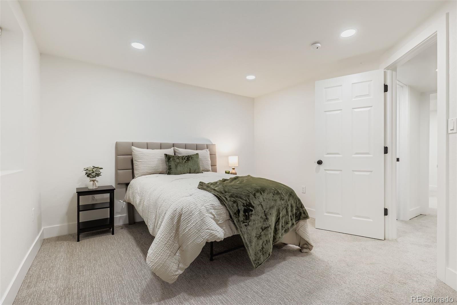 4465 Durham Court Denver, CO 80239 - Photo 22 of 28 a spacious bedroom with a bed and a night stand