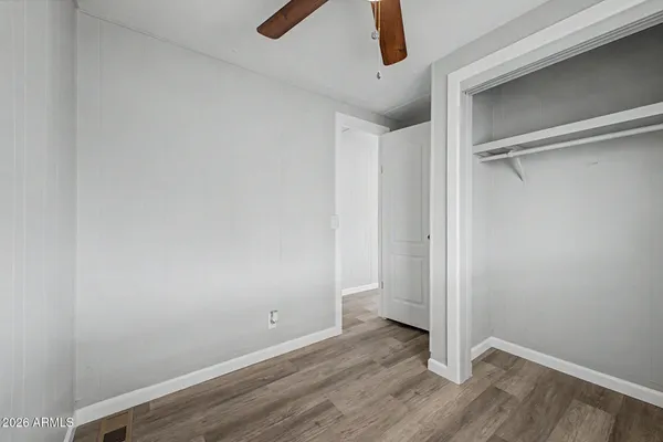 an empty room with wooden floor ceiling fan and windows