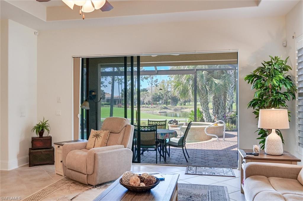 7587 Moorgate Point Way Naples, FL 34113 - Photo 4 of 50 Tray ceiling with recessed lighting and a ceiling fan, tile flooring, and sliding glass doors to a screened outdoor living area with a patio
