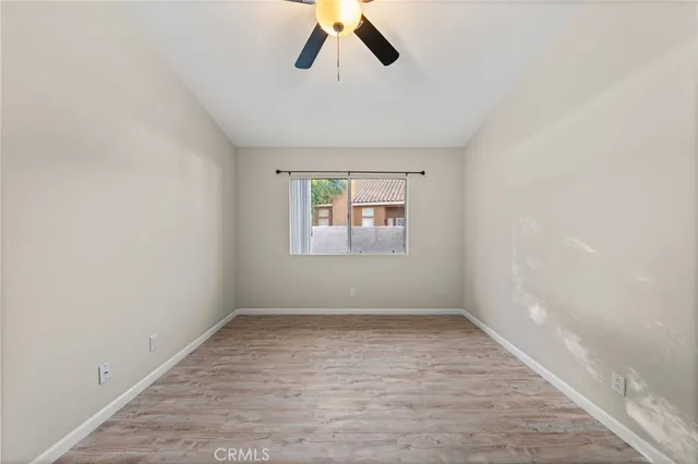 an empty room with a window and a ceiling fan