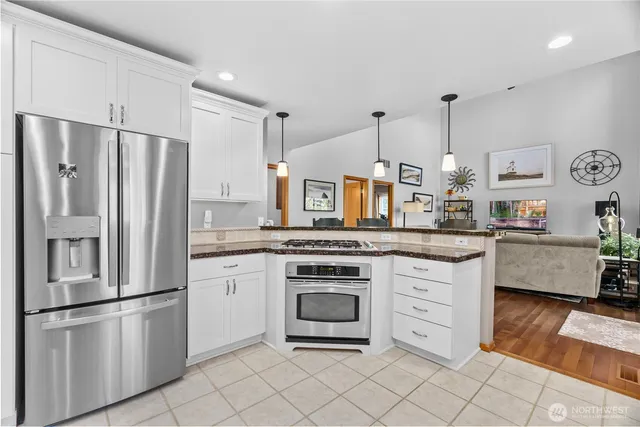 a kitchen with stainless steel appliances a stove a refrigerator and white cabinets