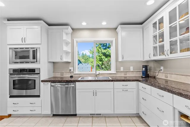 a kitchen with granite countertop white cabinets stainless steel appliances and a sink
