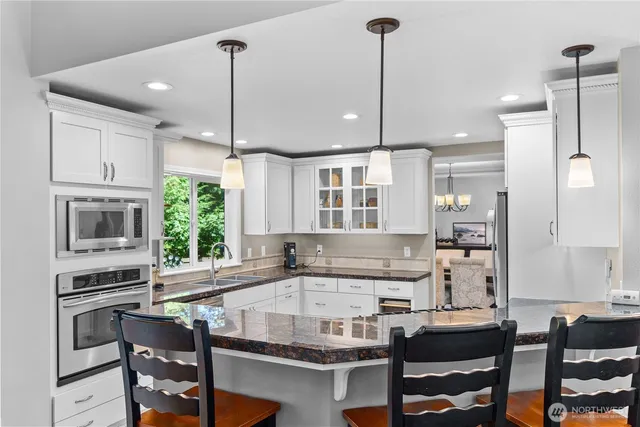 a kitchen with kitchen island granite countertop a table chairs stove a sink dishwasher and cabinets