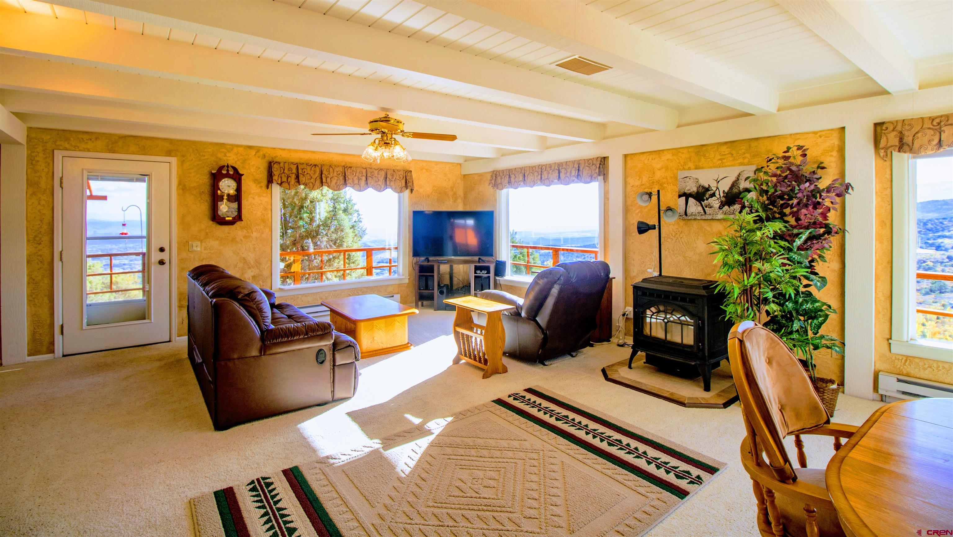 22211 Highway 65 Cedaredge, CO 81413 - Photo 14 of 35 a living room with furniture a flat screen tv and a floor to ceiling window