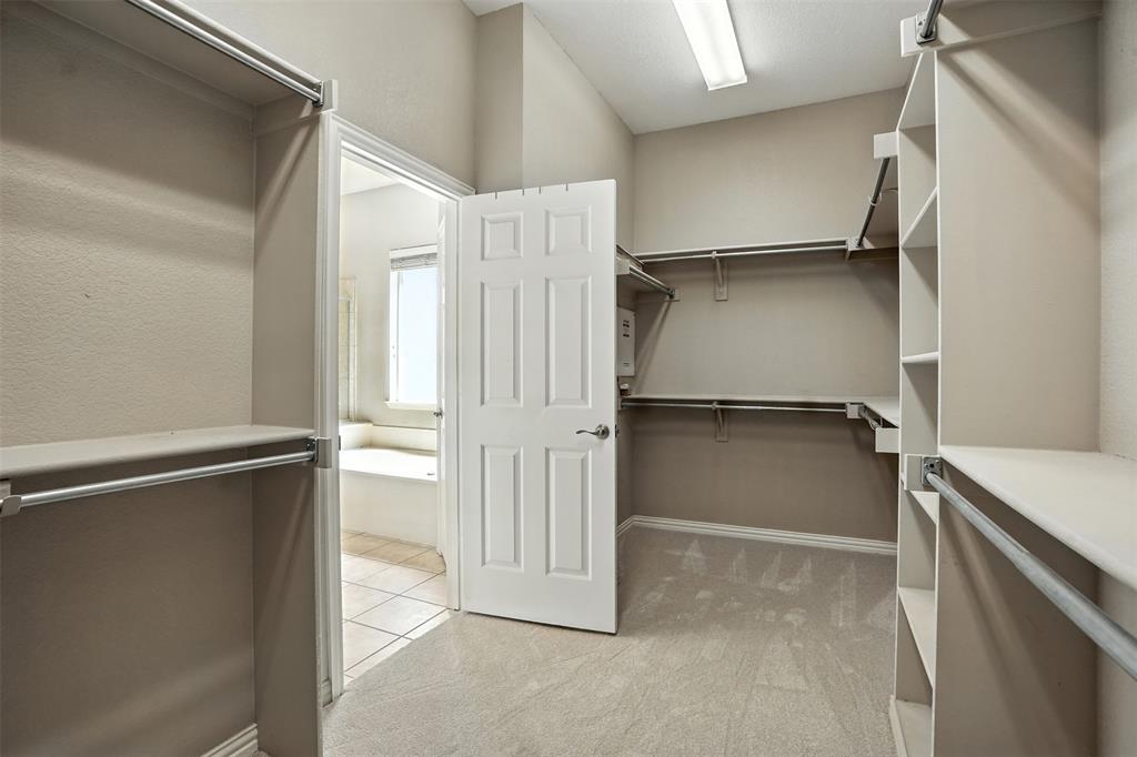 8220 Holliday Road Lantana, TX 76226 - Photo 24 of 40 Spacious walk-in closet featuring extensive built-in shelving and hanging rods, neutral wall tones, and carpet flooring