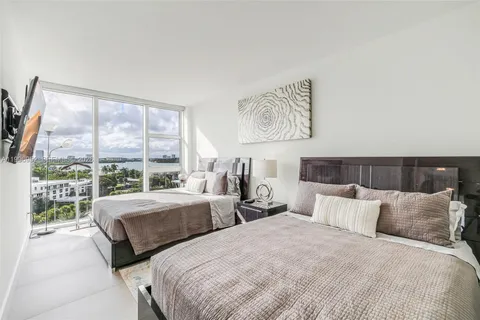 a bedroom with two large bed and a large window