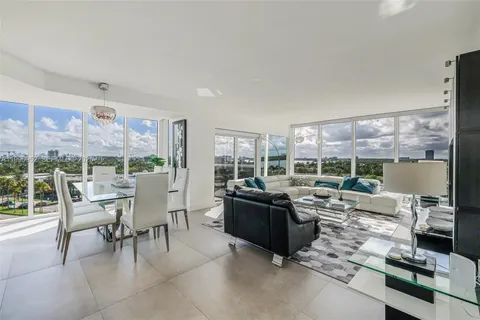 a living room with furniture large windows and wooden floor