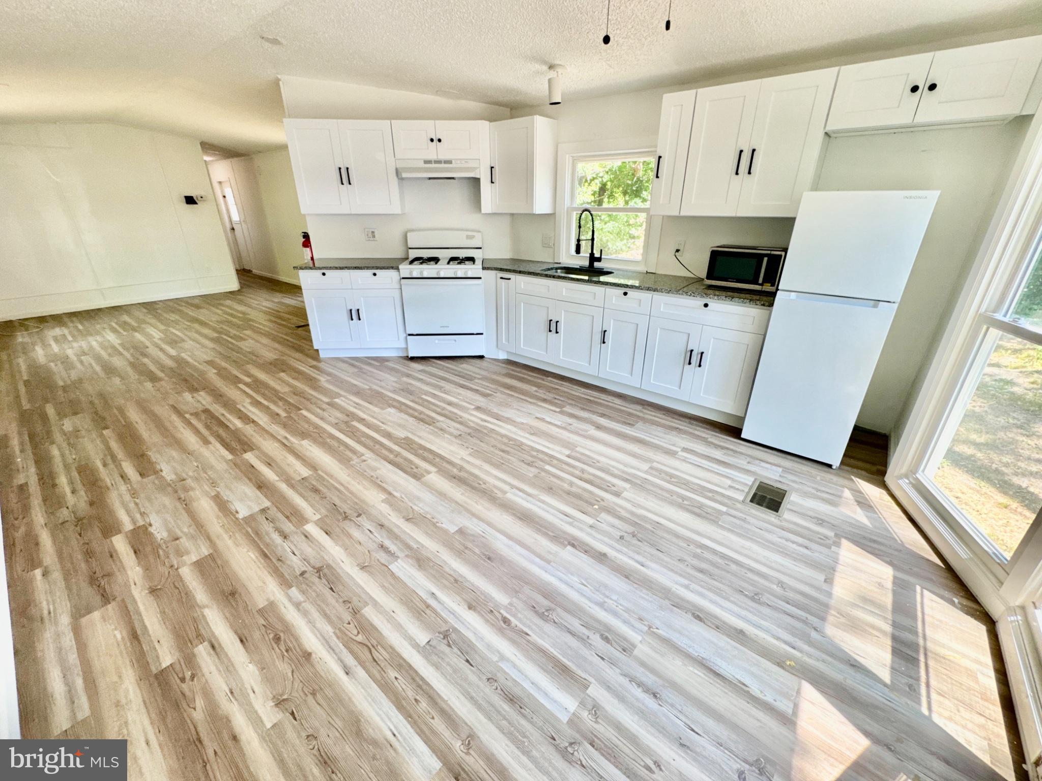 448 Evergreen Road Millville, NJ 08332 - Photo 11 of 25 a large kitchen with stainless steel appliances wooden floors and white walls