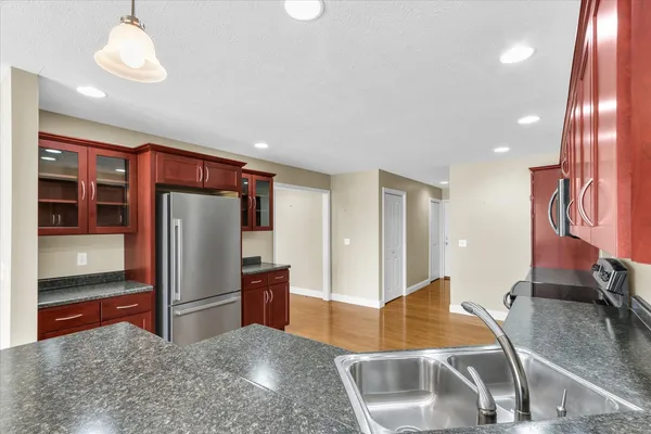 a kitchen with stainless steel appliances kitchen island granite countertop a refrigerator and a sink