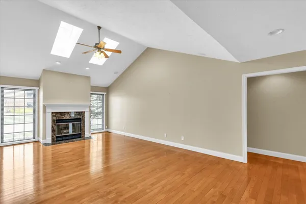 an empty room with wooden floor fireplace and window
