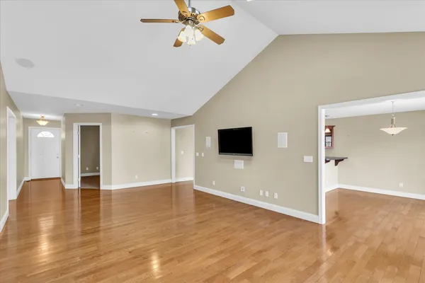 a view of an empty room with wooden floor and a window