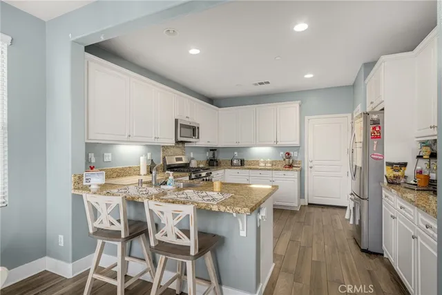a kitchen with kitchen island granite countertop a sink a counter space stainless steel appliances cabinets and a counter top space