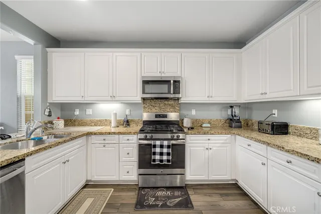 a kitchen with granite countertop white cabinets and stainless steel appliances