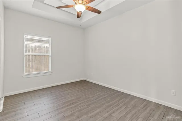 an empty room with wooden floor chandelier fan and windows