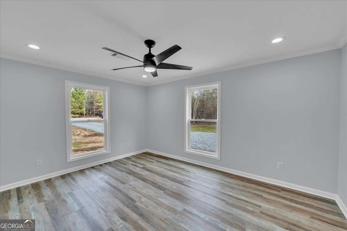 183 Bluegill Road Vienna, GA 31092 - Photo 22 of 67 an empty room with wooden floor chandelier fan and windows