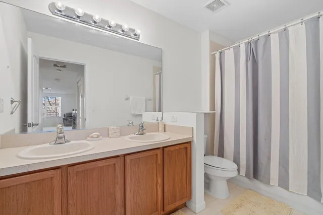 a bathroom with a double vanity sink toilet and a mirror