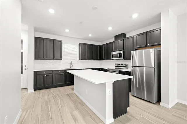 a kitchen with stainless steel appliances granite countertop a refrigerator stove a sink dishwasher and wooden cabinets with wooden floor