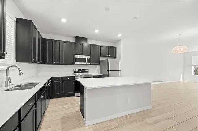 a kitchen with kitchen island granite countertop a sink stove top oven and refrigerator