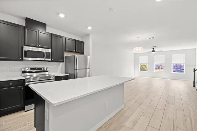 a large kitchen with stainless steel appliances a sink dishwasher a refrigerator a microwave oven with cabinets and wooden floor