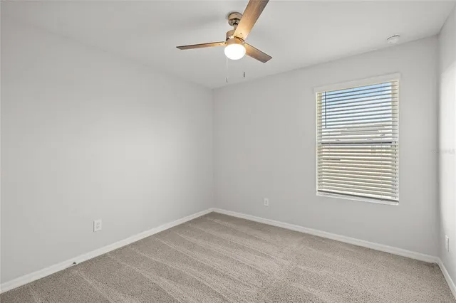 an empty room with a window and a fan