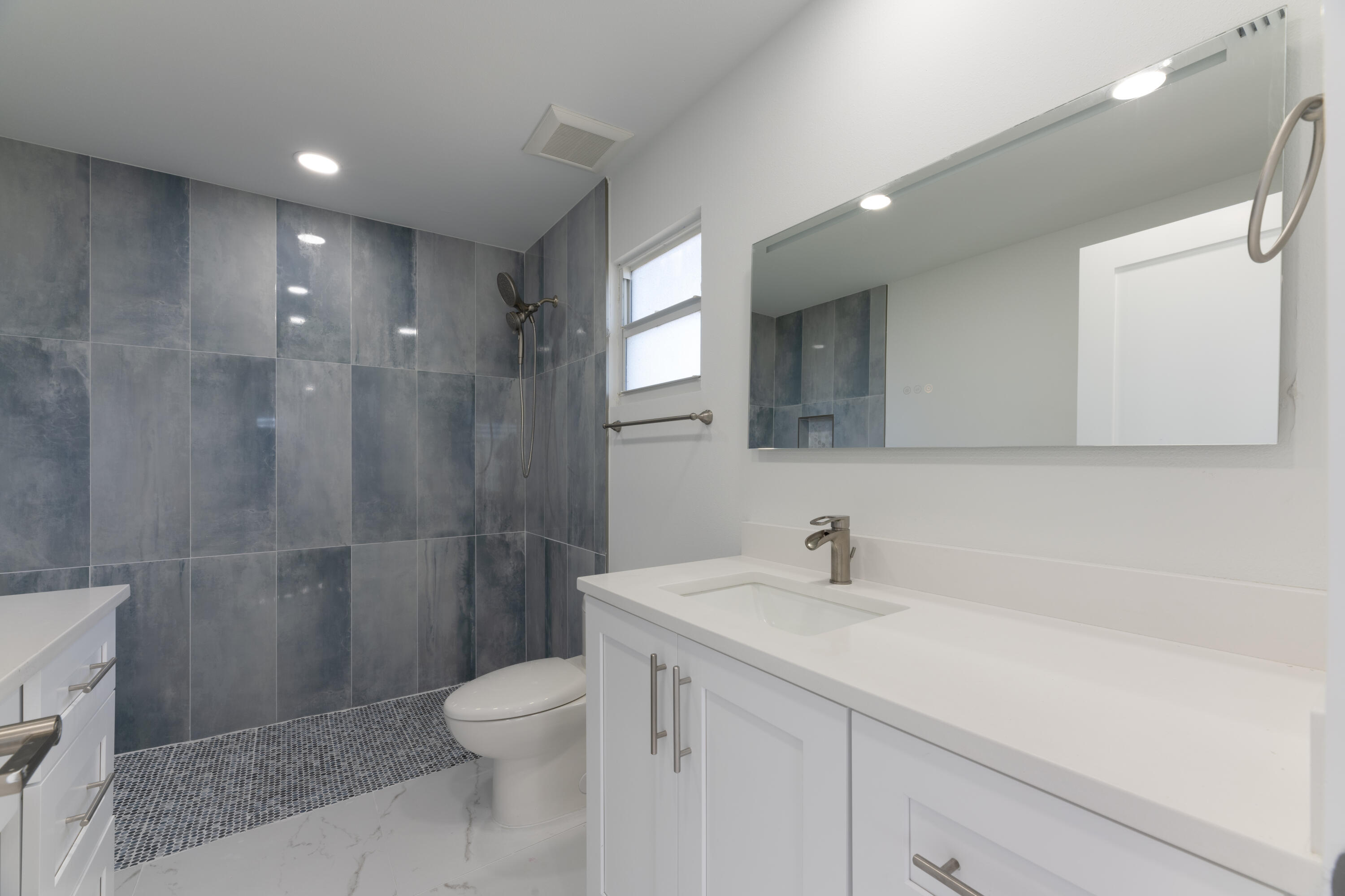 13757 Cocoanut Avenue Juno Beach, FL 33408 - Photo 12 of 31 a bathroom with a toilet a sink a mirror a shower and vanity