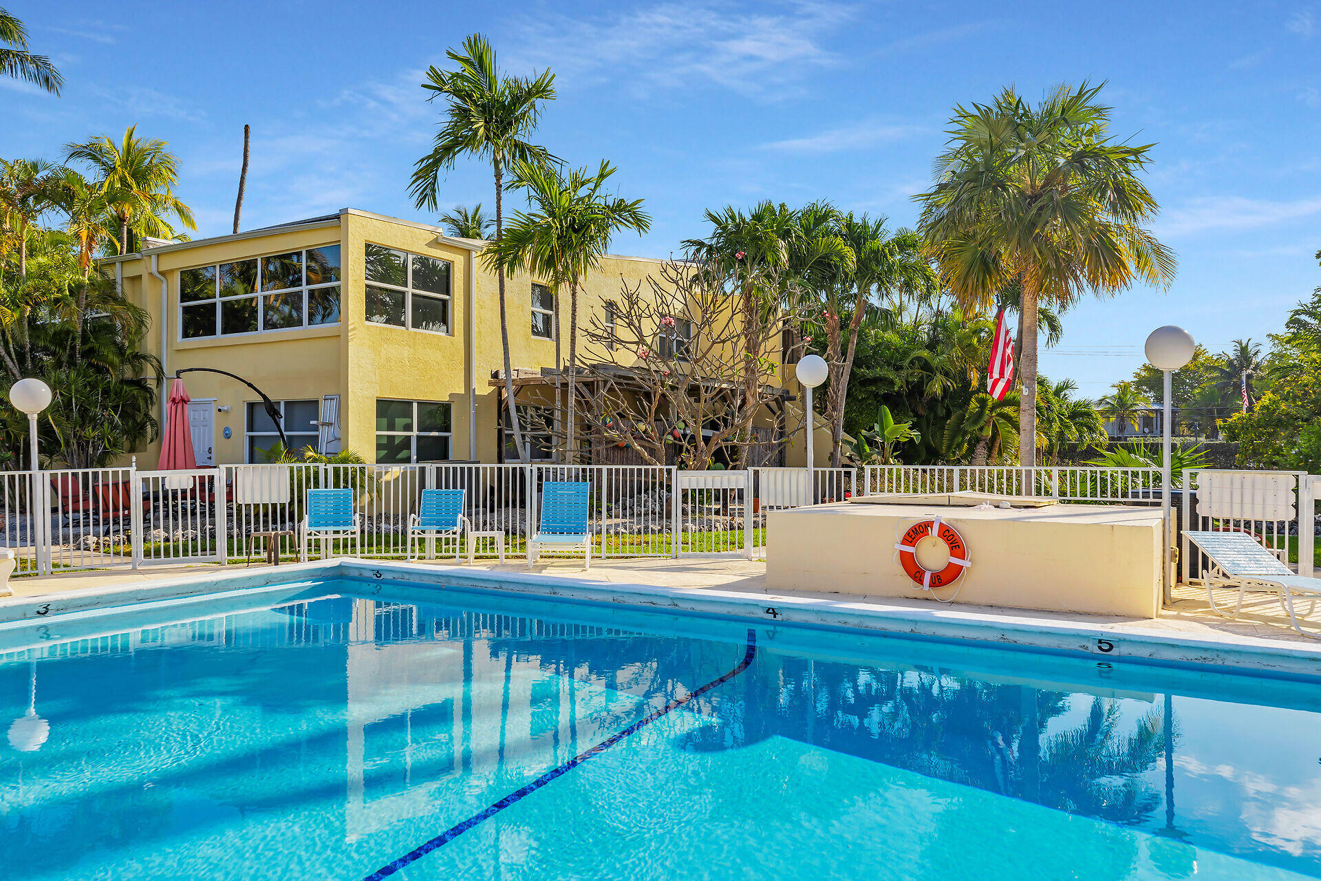 591 Sombrero Beach Road, Unit 8B Marathon, FL 33050 - Photo 27 of 43 a view of a swimming pool with a lawn chairs under palm trees