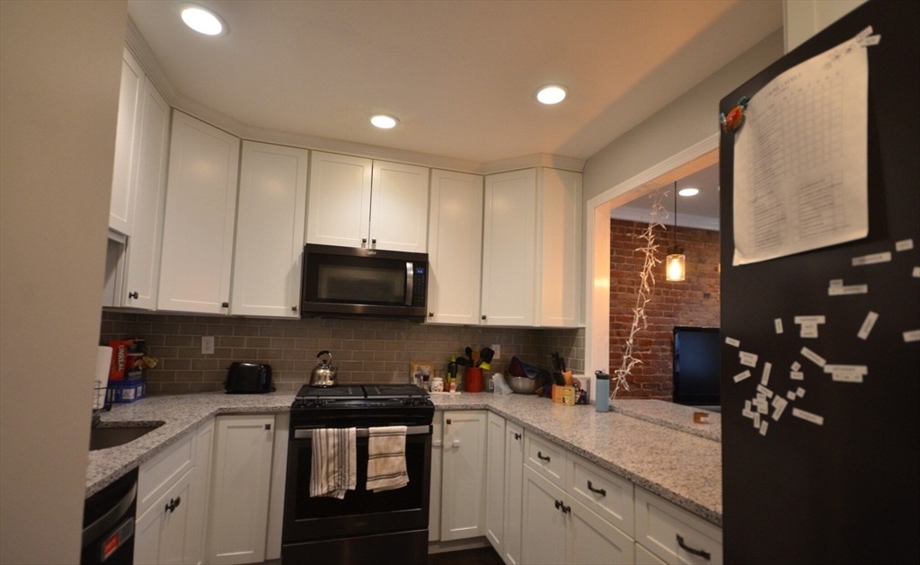 60 Florida Street, Unit 2 Boston, MA 02124 - Photo 9 of 25 a kitchen with granite countertop white cabinets and stainless steel appliances
