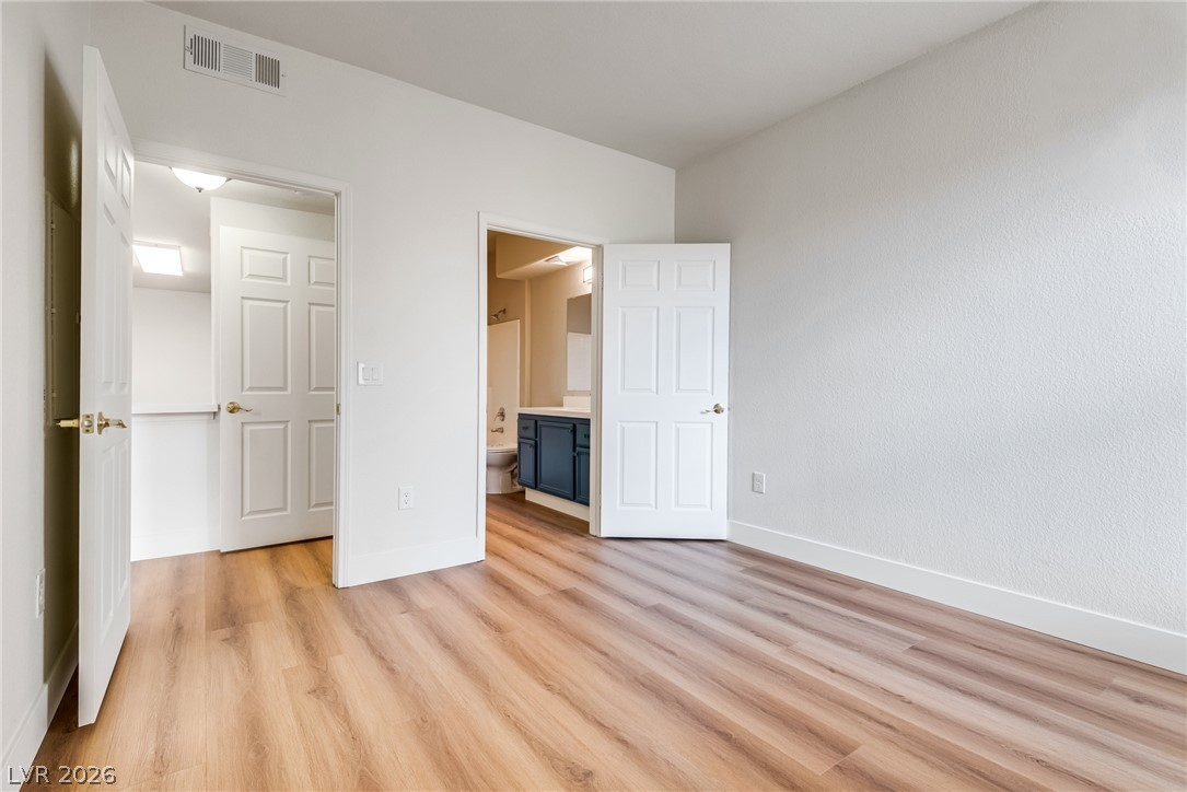 10550 West Alexander Road, Unit 2174 Las Vegas, NV 89129 - Photo 23 of 28 Smooth wood-plank flooring runs throughout this bedroom featuring private access to an adjacent bathroom.