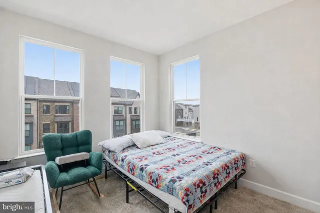 a bedroom with a bed a couch and a dresser next to a window