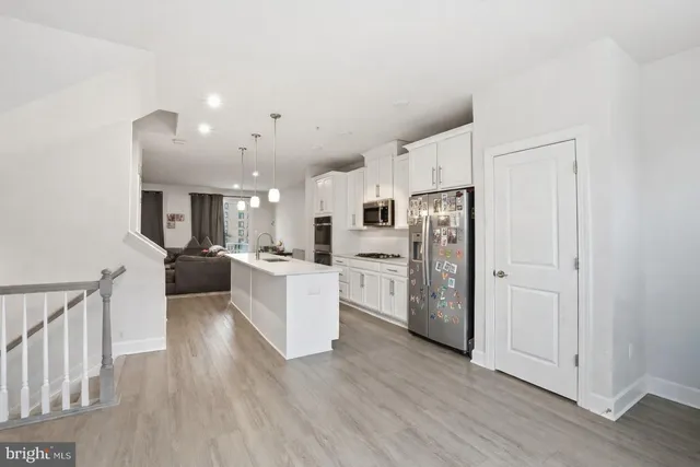 a large white kitchen with stainless steel appliances refrigerator a stove top oven with wooden floors