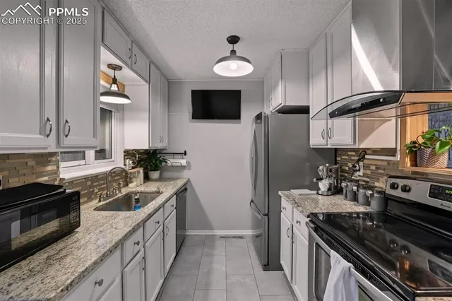 a kitchen with stainless steel appliances granite countertop a stove a sink and a refrigerator