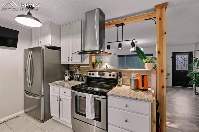 a kitchen with stainless steel appliances granite countertop a refrigerator a stove and a sink with wooden floor
