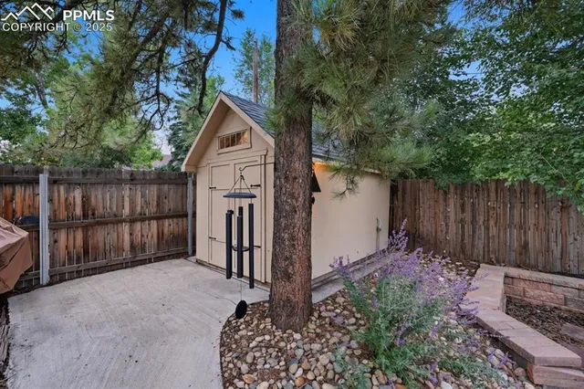 a view of backyard with small cabin and wooden fence