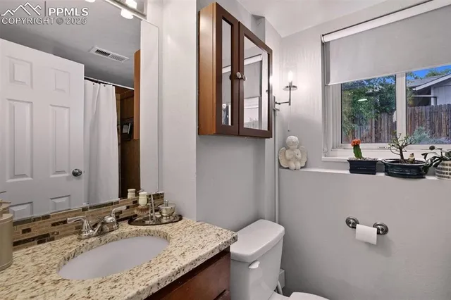 a bathroom with a granite countertop sink a toilet and a mirror