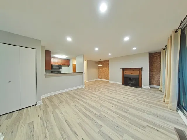 a view of empty room with wooden floor and fireplace