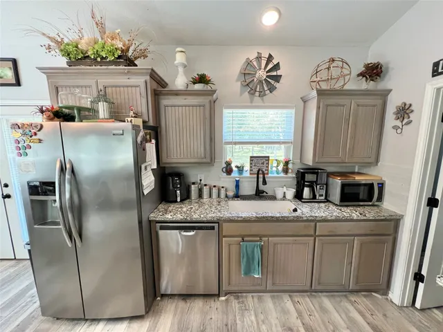 a kitchen with stainless steel appliances granite countertop a refrigerator a sink a stove a dining table and chairs