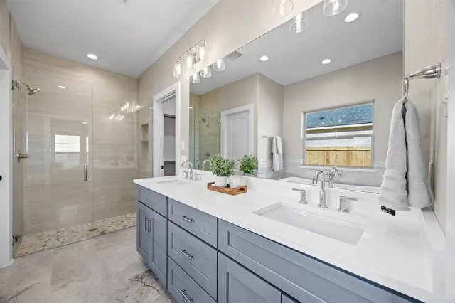 a bathroom with a sink double vanity granite tub shower and a mirror