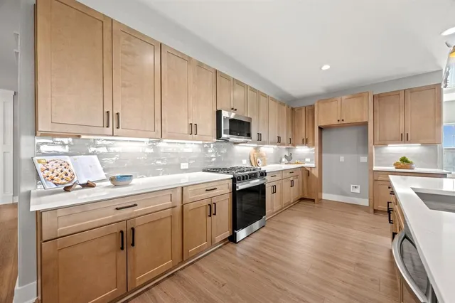 a large kitchen with stainless steel appliances granite countertop a lot of counter space and wooden floors