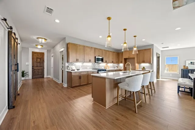 a kitchen with stainless steel appliances a dining table chairs stove refrigerator and cabinets