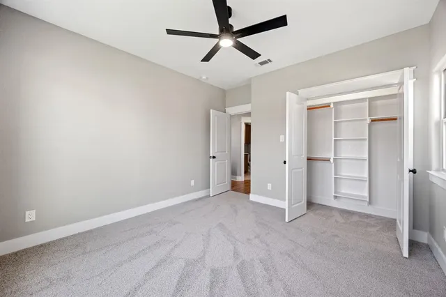 an empty room with closet and a ceiling fan