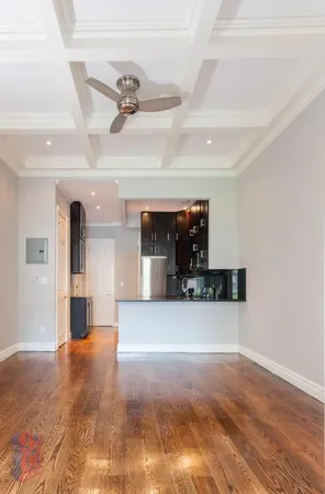 a view of a room with a fireplace a ceiling fan and wooden floor