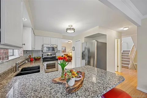 a kitchen with stainless steel appliances granite countertop a sink dishwasher stove refrigerator and cabinets
