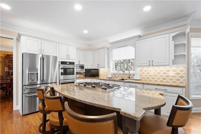 a kitchen with kitchen island a stove a table and chairs in it