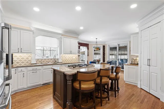 a kitchen with granite countertop a dining table chairs and white cabinets