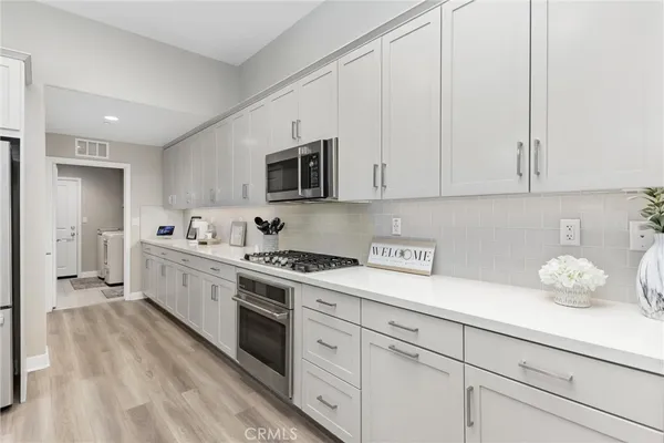 a kitchen with cabinets stainless steel appliances a sink and wooden floor