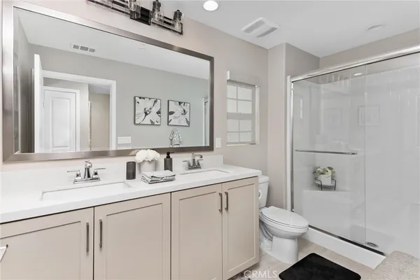 a bathroom with a toilet a sink a mirror a vanity and shower