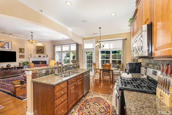 a kitchen with stainless steel appliances granite countertop a stove and a view of living room