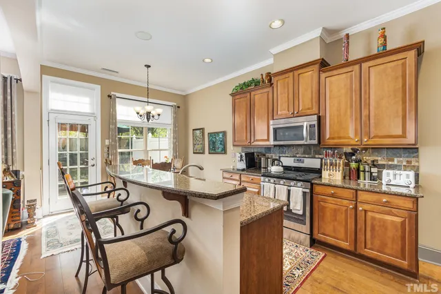 a kitchen with stainless steel appliances granite countertop a stove top oven a sink dishwasher and white cabinets with wooden floor