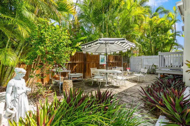 a view of a patio with table and chairs under an umbrella with large trees